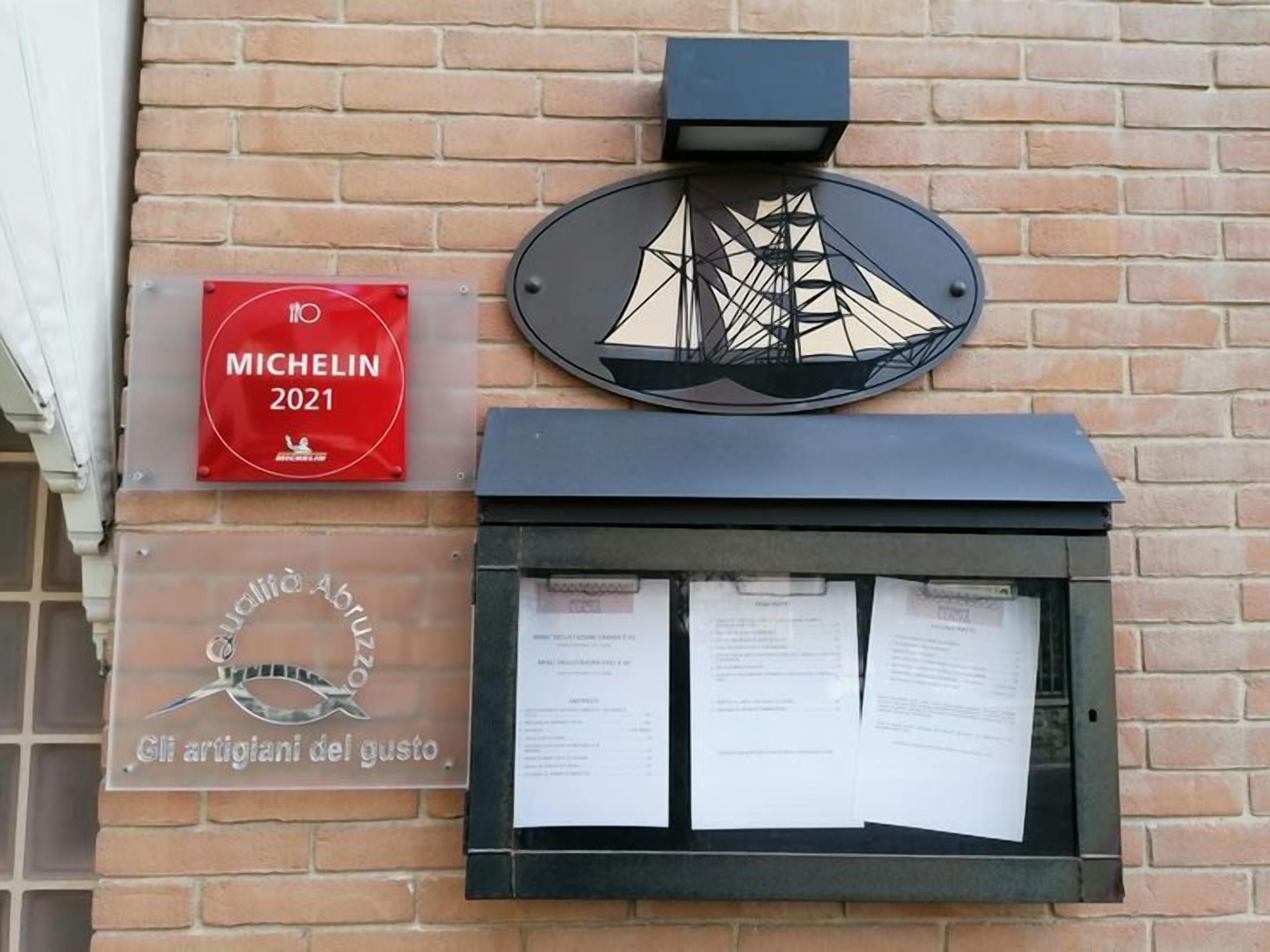 A building facade with a Michelin 2021 award sign, a decorative metal plate, and a window with papers.