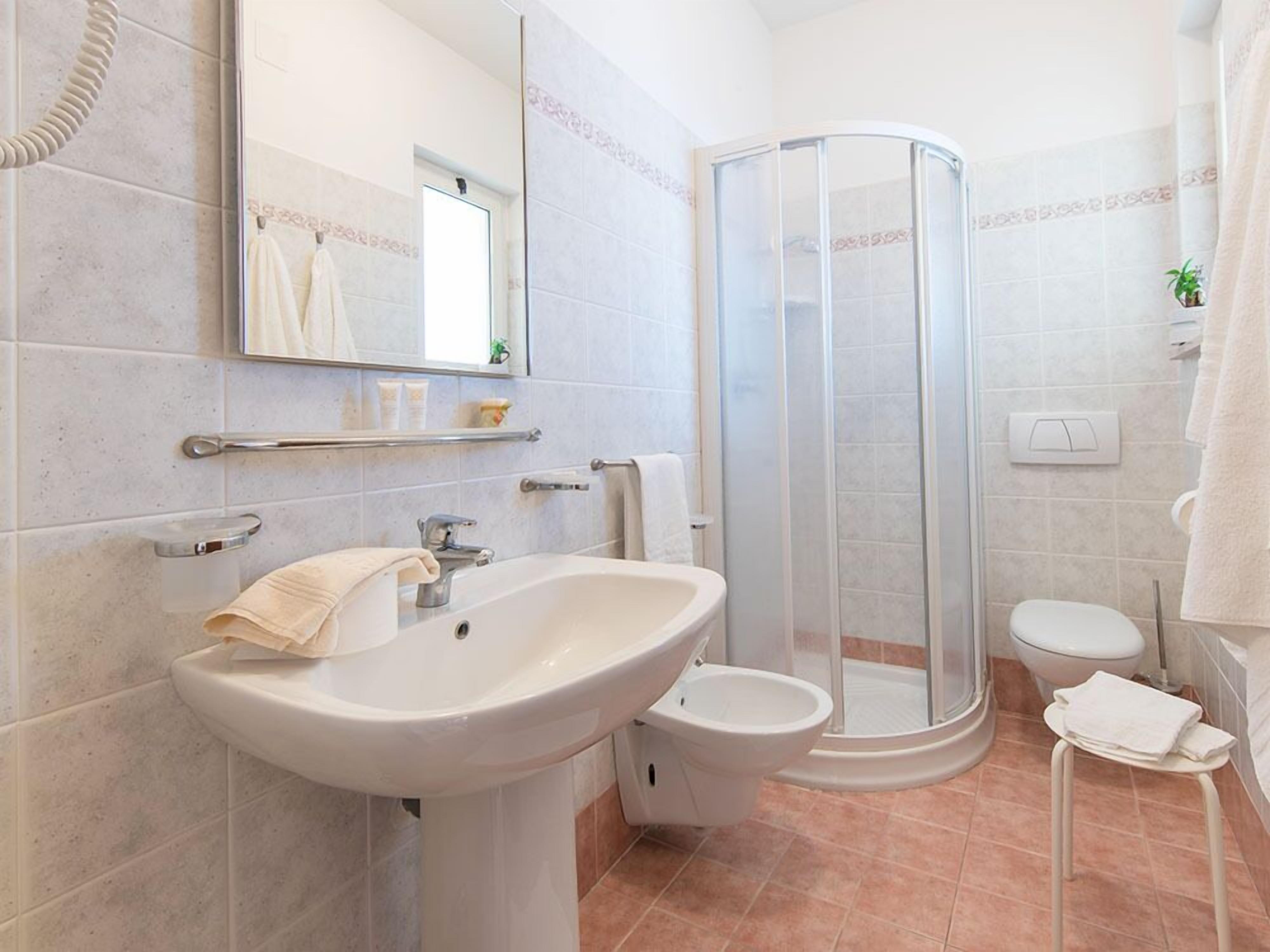 Une salle de bain moderne équipée d’un lavabo, de toilettes et d’une douche.