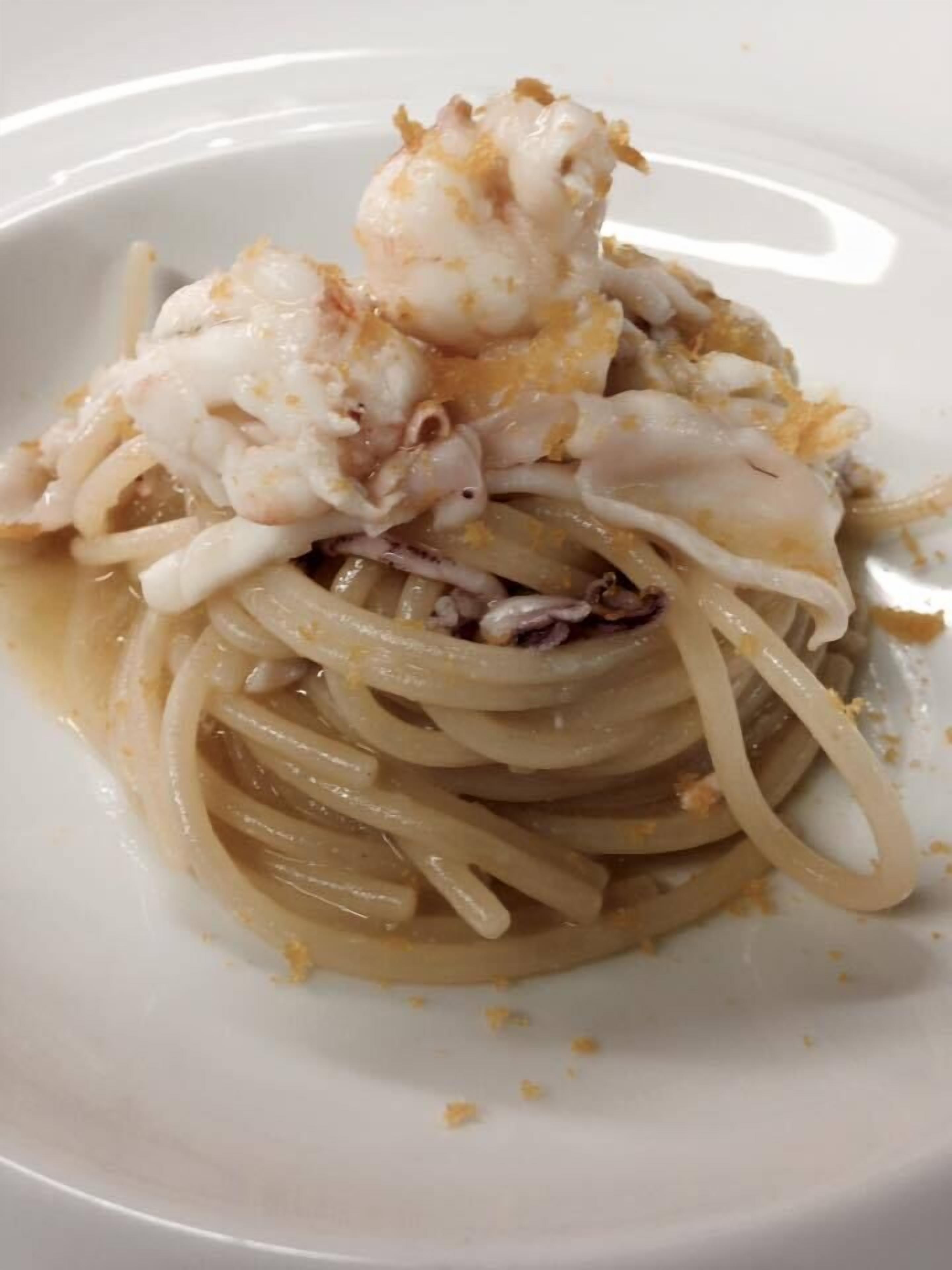 A plate of spaghetti with a large piece of lobster on top.