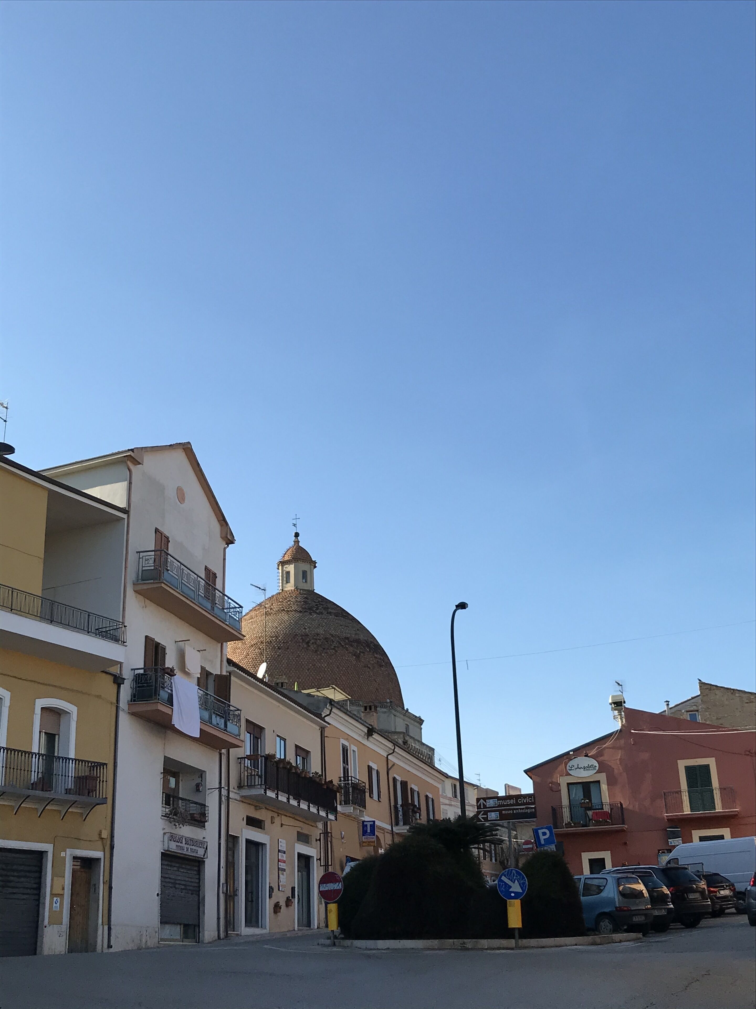 Una vista di strada con un edificio importante, caratterizzato da una cupola e balconi.