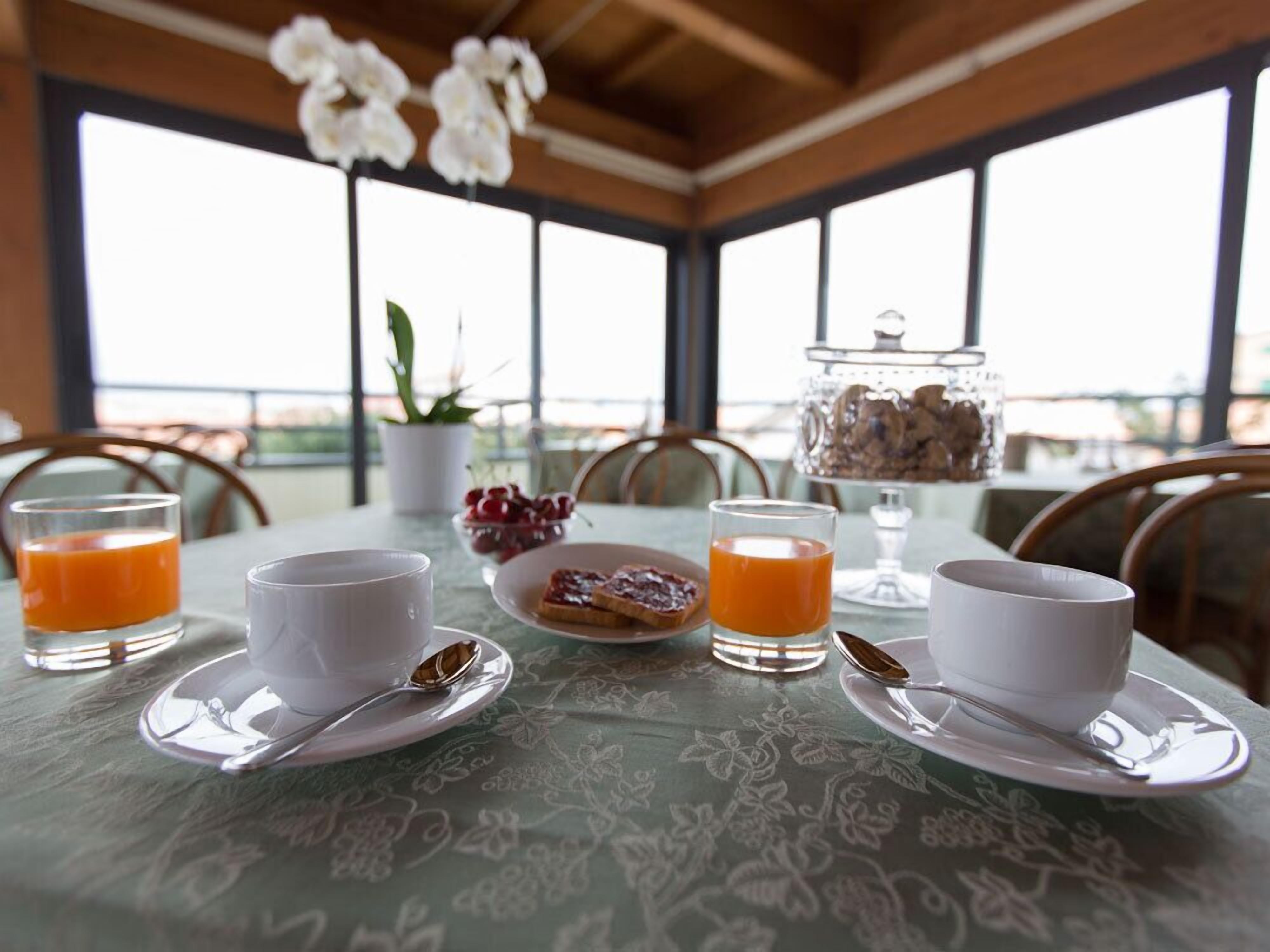 Una mesa de desayuno con dos vasos de jugo de naranja, un plato de tostadas, un bol de cerezas y un vaso de leche.