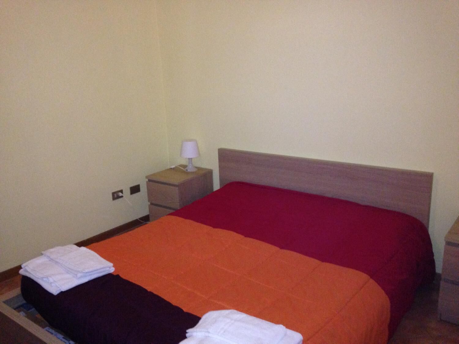 Una habitación de hotel con una cama individual, una mesita de noche con lámpara y una cómoda pequeña.