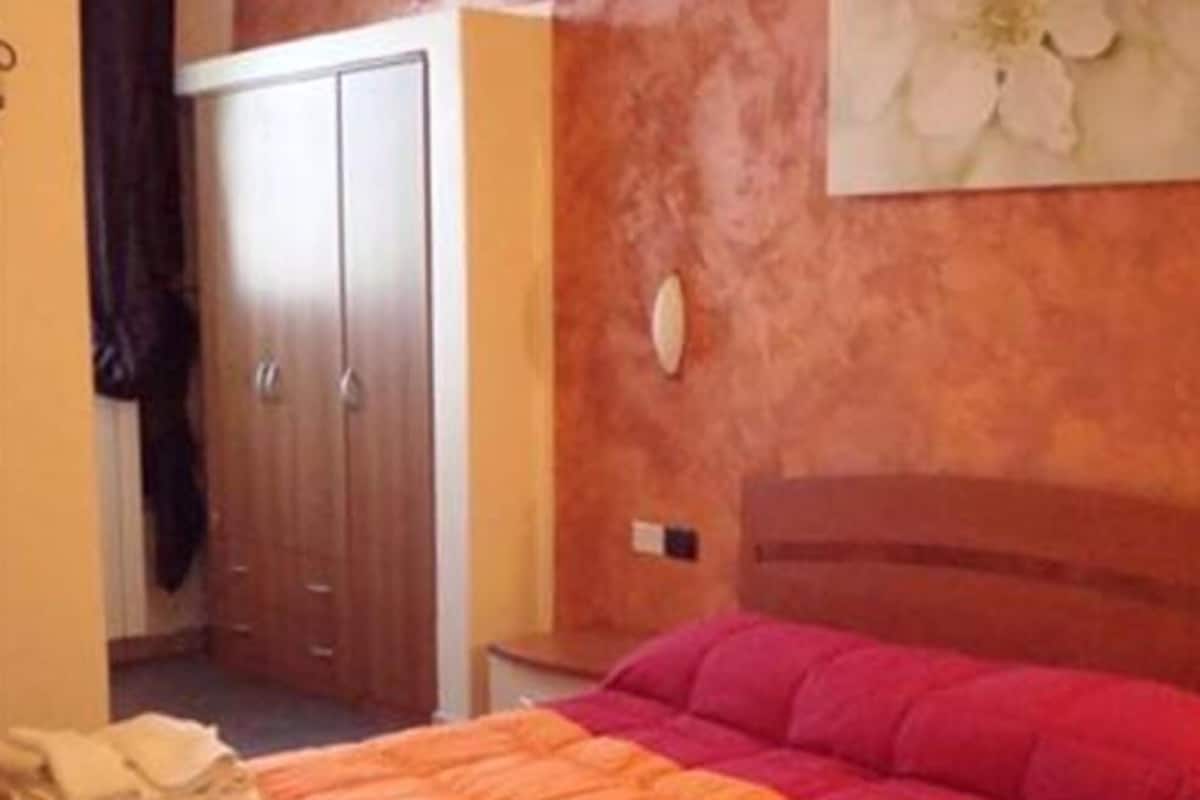 Un dormitorio con cama, armario y mesita de noche.