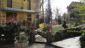 A yellow building with a balcony, surrounded by potted plants and a stone pathway. - La Pergola (Zibido San Giacomo)