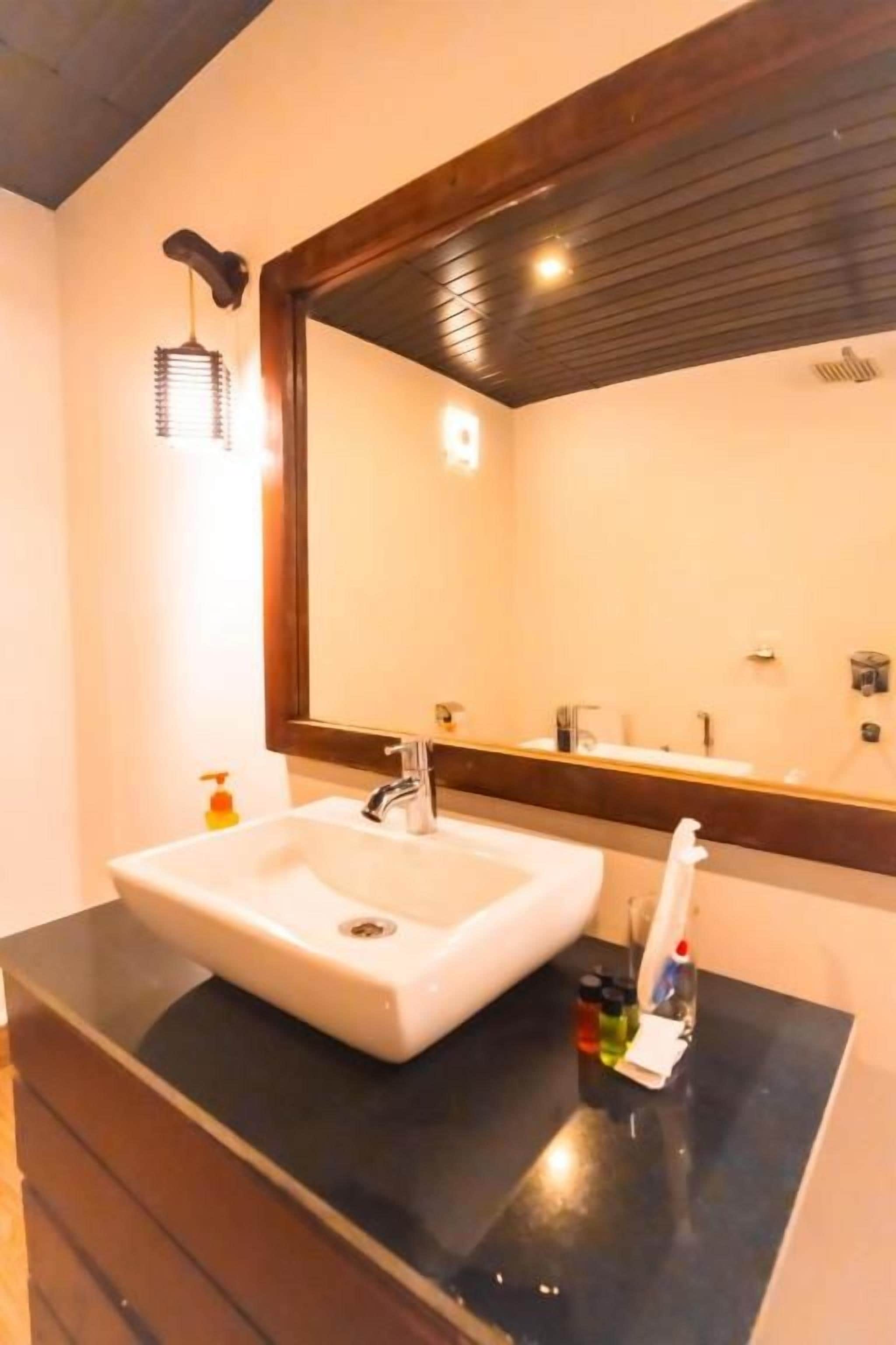 A bathroom with a white sink, a mirror, and a black countertop.