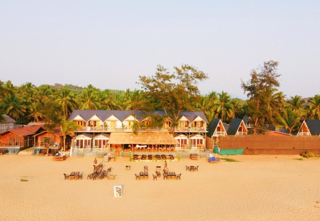 A beachfront hotel with multiple-story buildings, outdoor seating, and palm trees in the background.