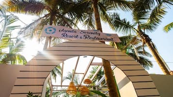 Letrero de 'Agenda Serenity Resort & Restaurant' con un arco de palmeras.