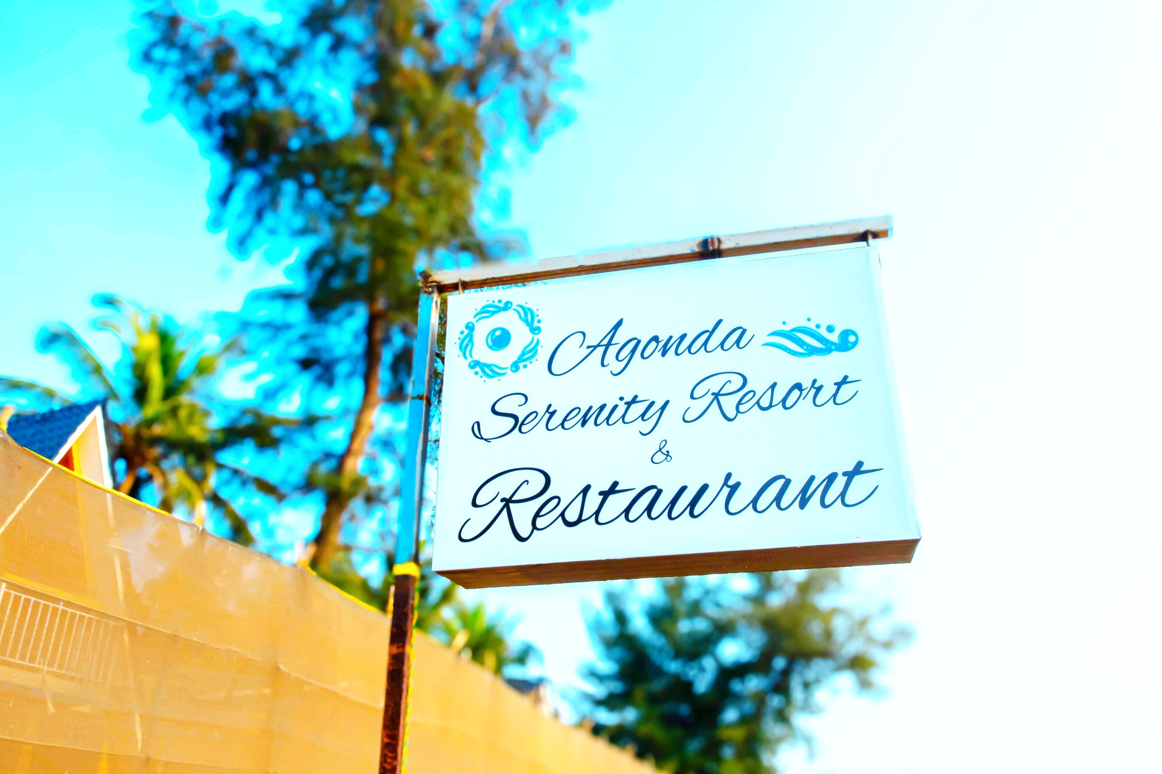 Een bord met 'Agenda Serenity Resort & Restaurant', inclusief een logo en tekst.