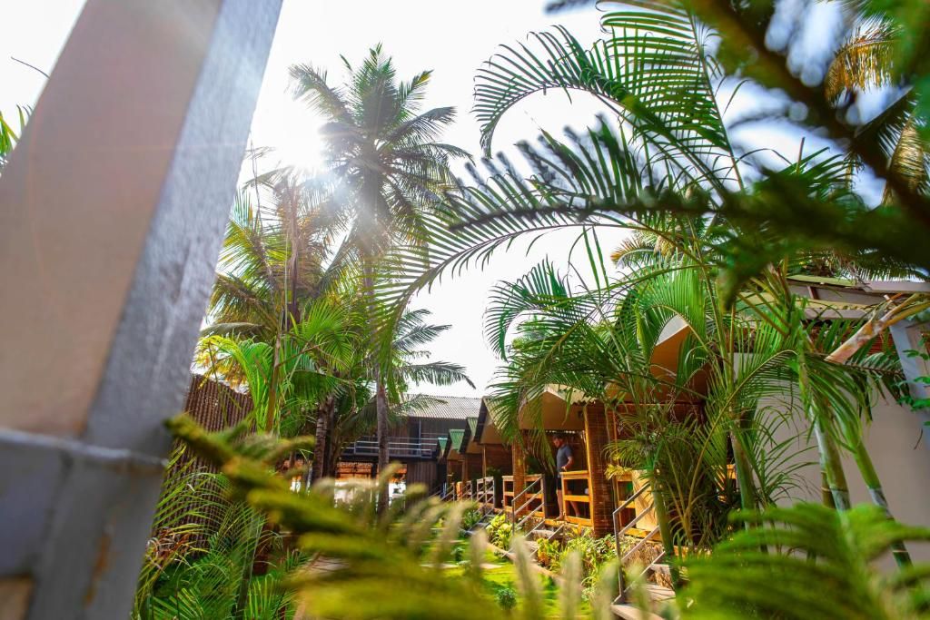 A tropical resort with a pool, palm trees, and a covered outdoor area.