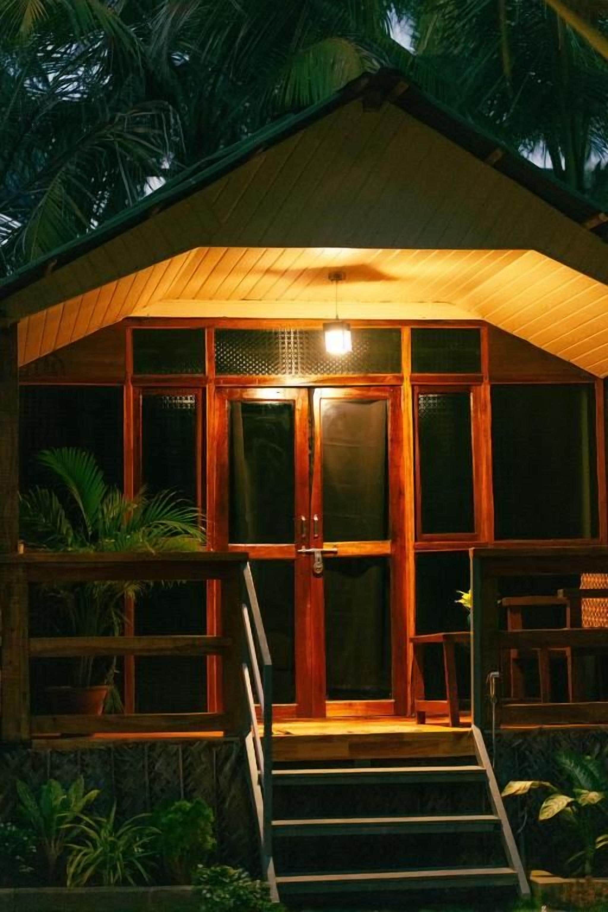 A wooden building with a porch and steps leading to a door.