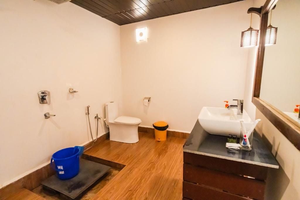 A bathroom with a toilet, sink, and blue bucket.