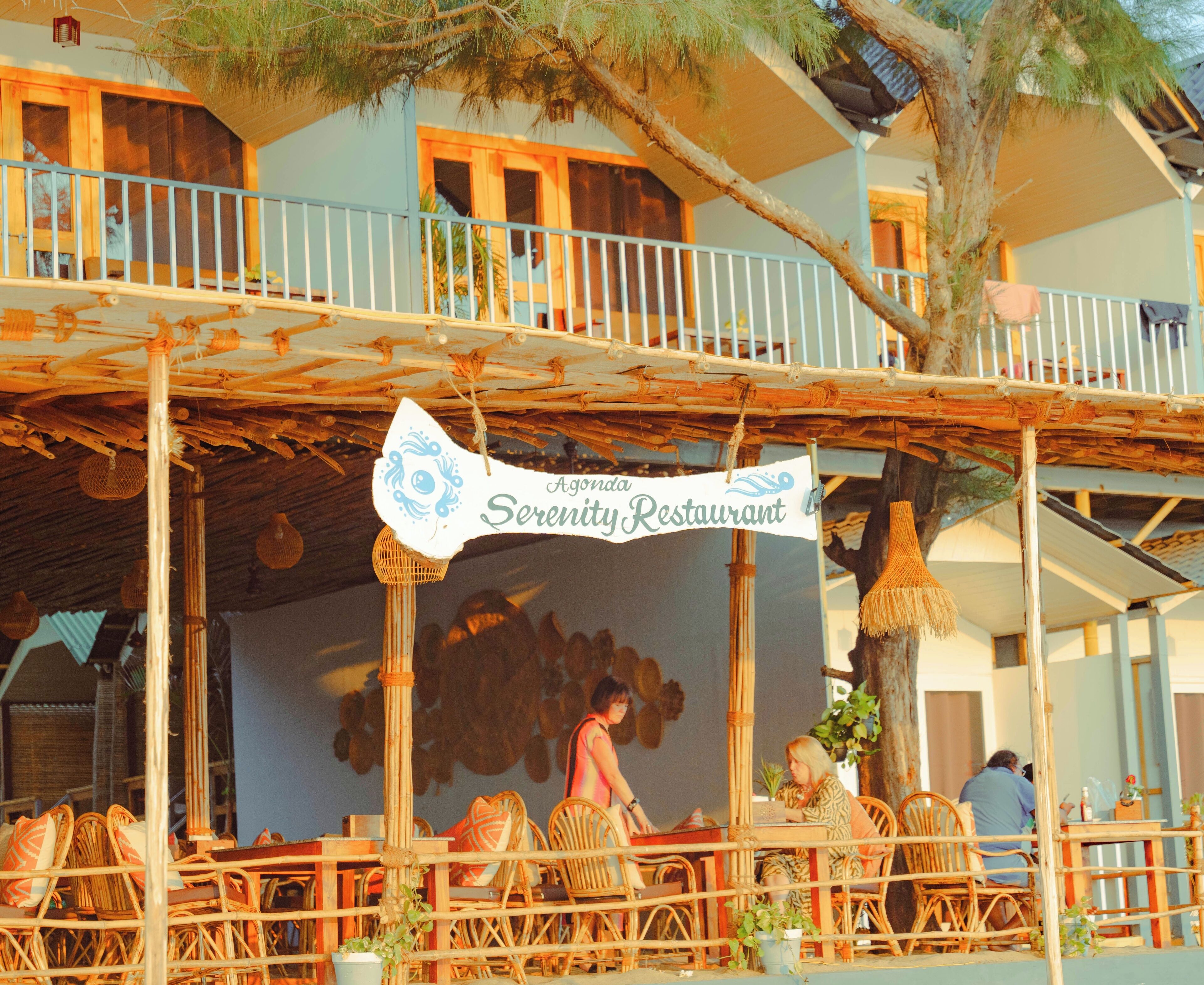 A restaurant with a bamboo roof and wicker furniture.