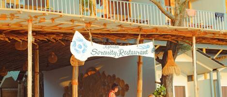 A restaurant with a bamboo roof and wicker furniture.