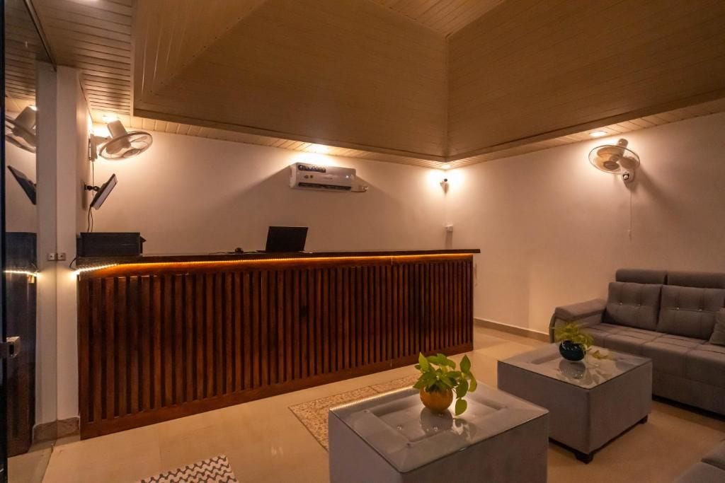 A reception area with a wooden reception desk, a grey sofa, and a coffee table with a plant.
