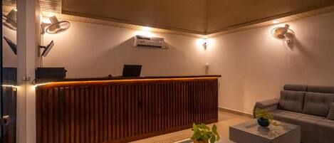 A reception area with a wooden reception desk, a grey sofa, and a coffee table with a plant.