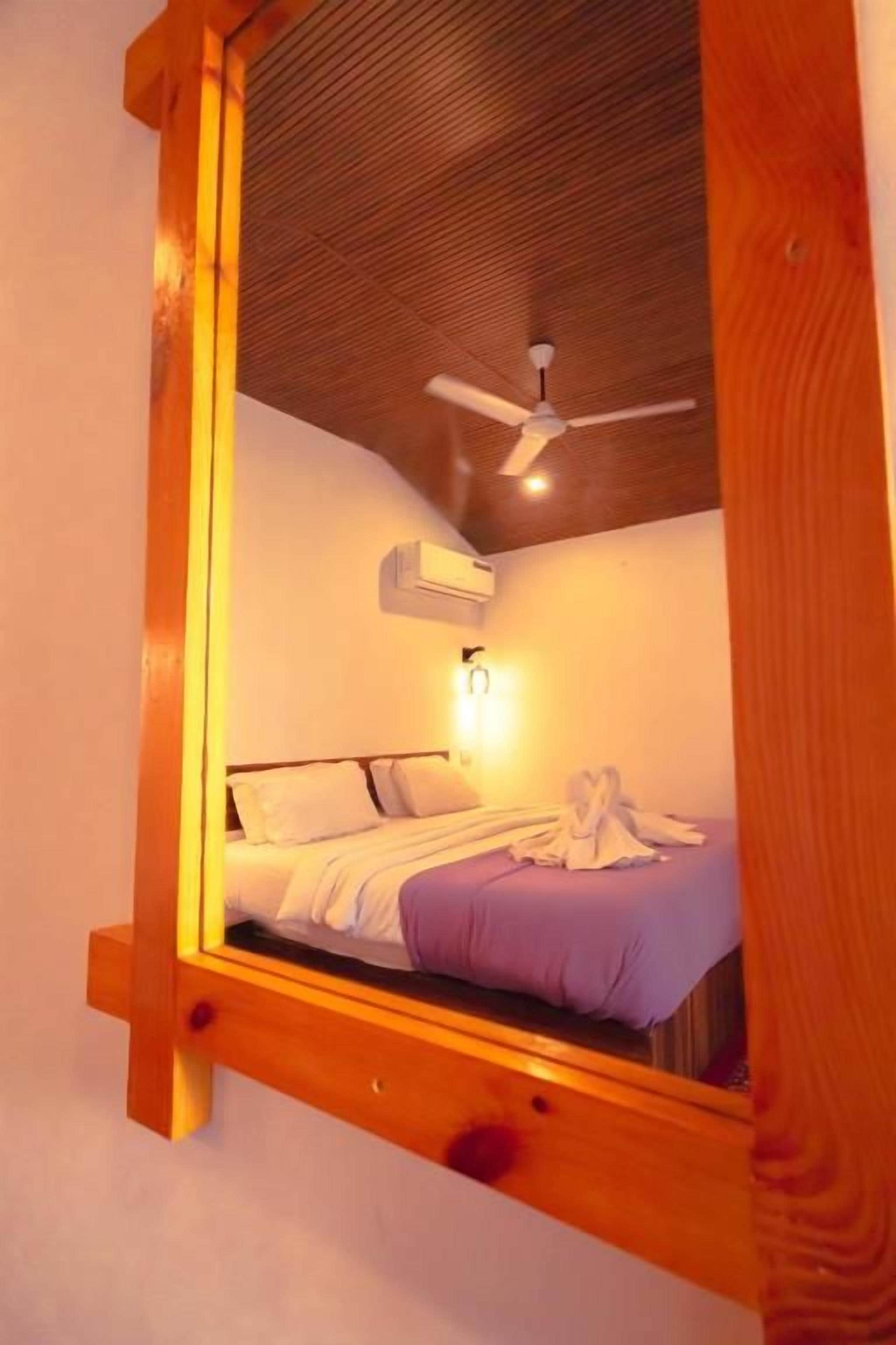 A bedroom with a bed, an air conditioning unit, a ceiling fan, and a wooden headboard.