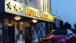 Un hôtel appelé « HÔTEL GRAVANA », avec une voiture rouge garée devant.