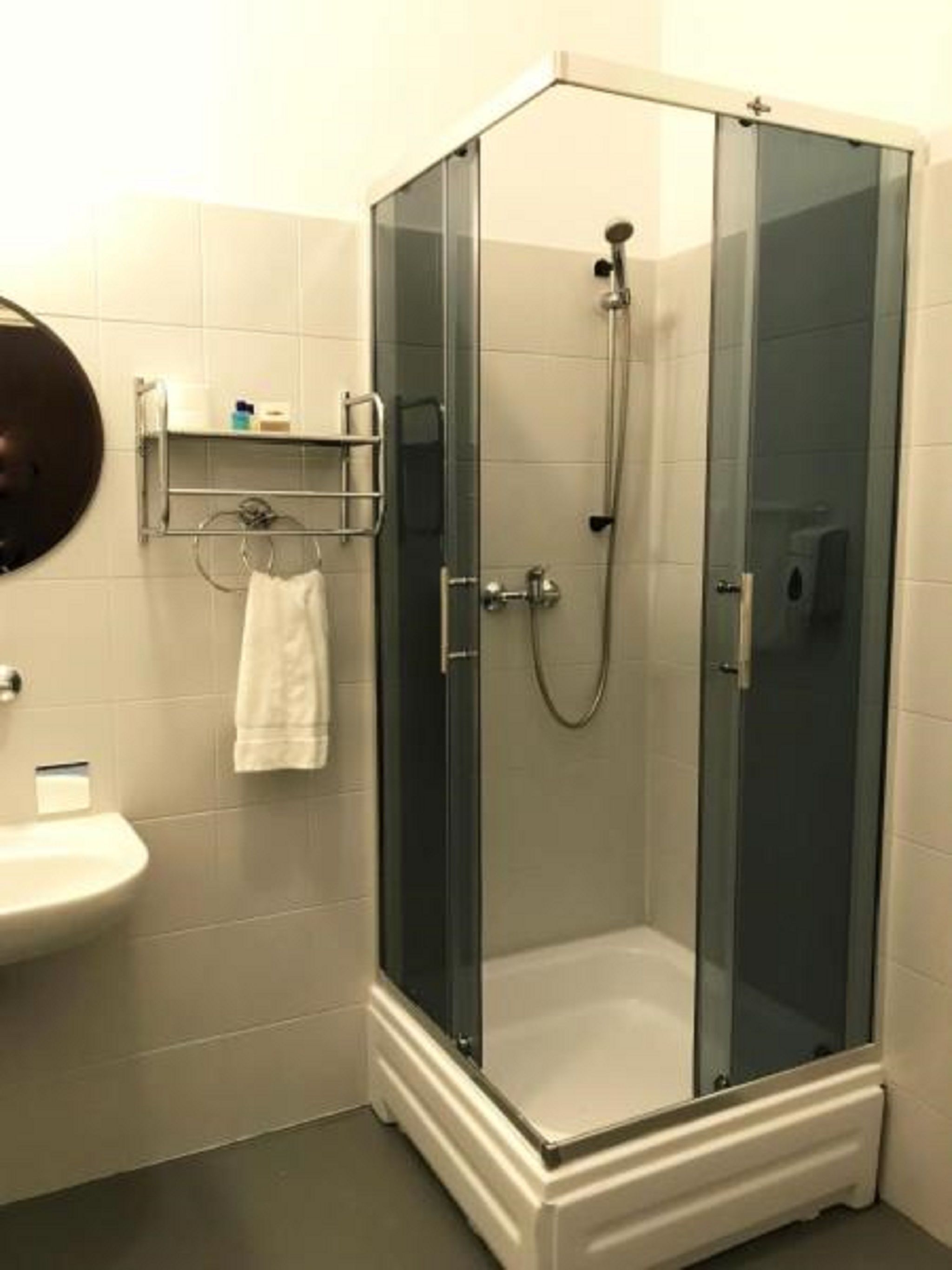 A glass-enclosed shower with a white sink and a towel rack.
