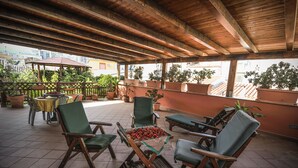 An outdoor patio with wooden furniture, potted plants, and a table with a red cloth. - Hotel Piccolo di Corduneanu Aurora (Termini Imerese)