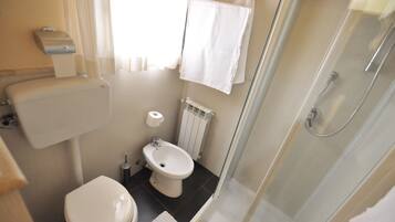 A compact bathroom with a toilet, bidet, and a glass-enclosed shower.