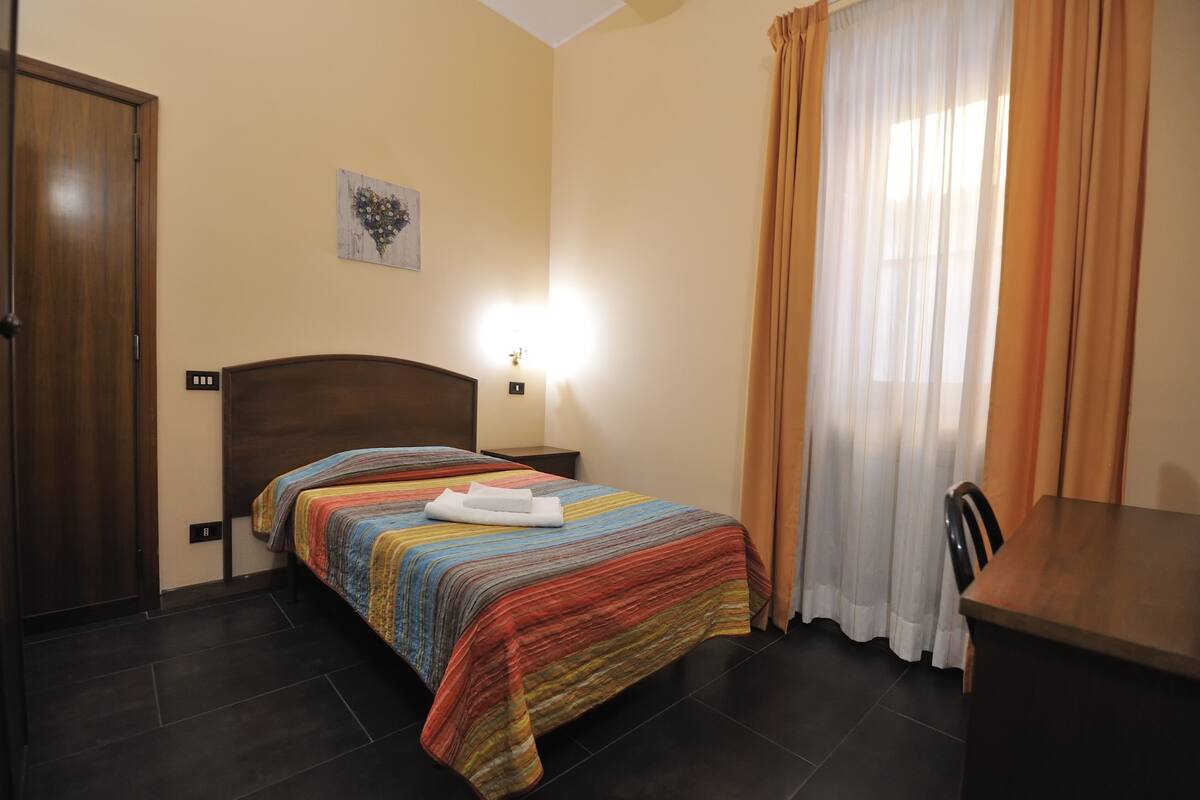 Een hotelkamer met een bed, nachtkastje, tafel en stoel.