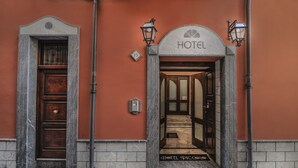 A hotel entrance with a wooden door, a sign above the door, and two street lamps. - Hotel Piccolo di Corduneanu Aurora (Termini Imerese)