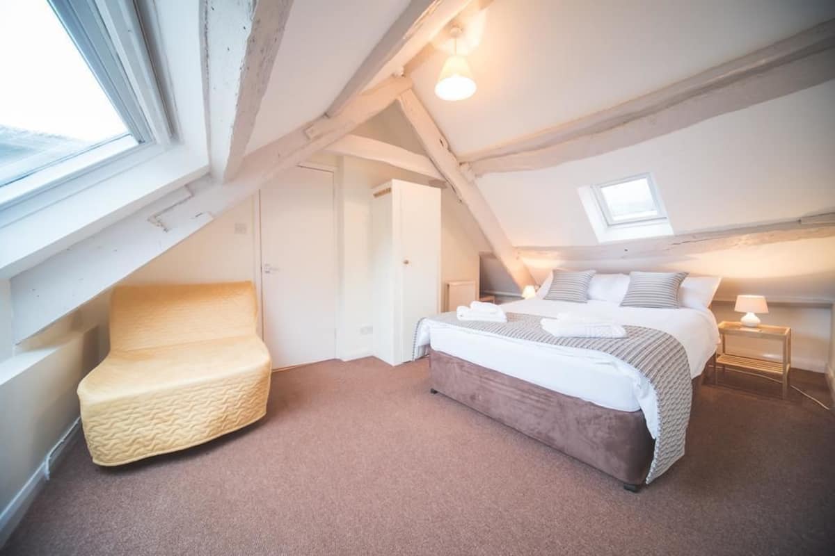 Une chambre à coucher avec un lit, une chaise, une table de chevet et une fenêtre.
