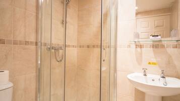 Un baño con ducha de vidrio, lavamanos e inodoro.