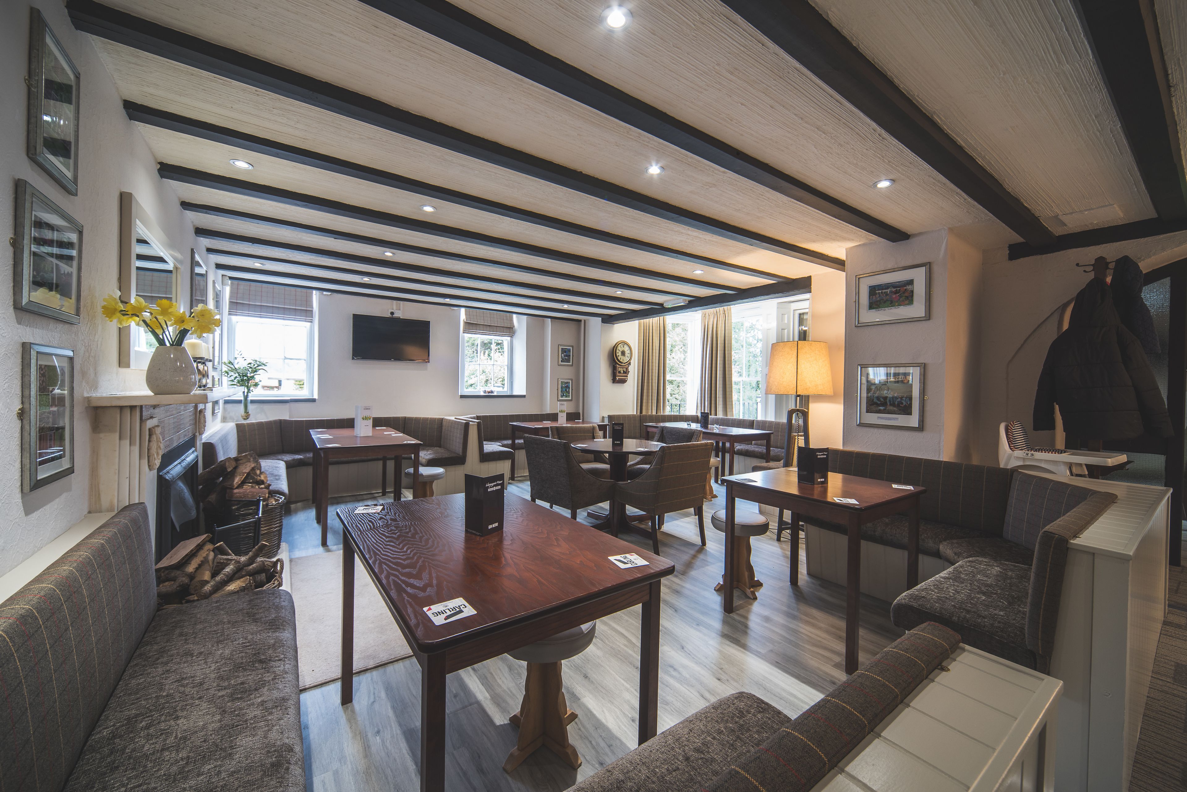 A spacious dining area with multiple tables and chairs, a sofa, and a television mounted on the wall.