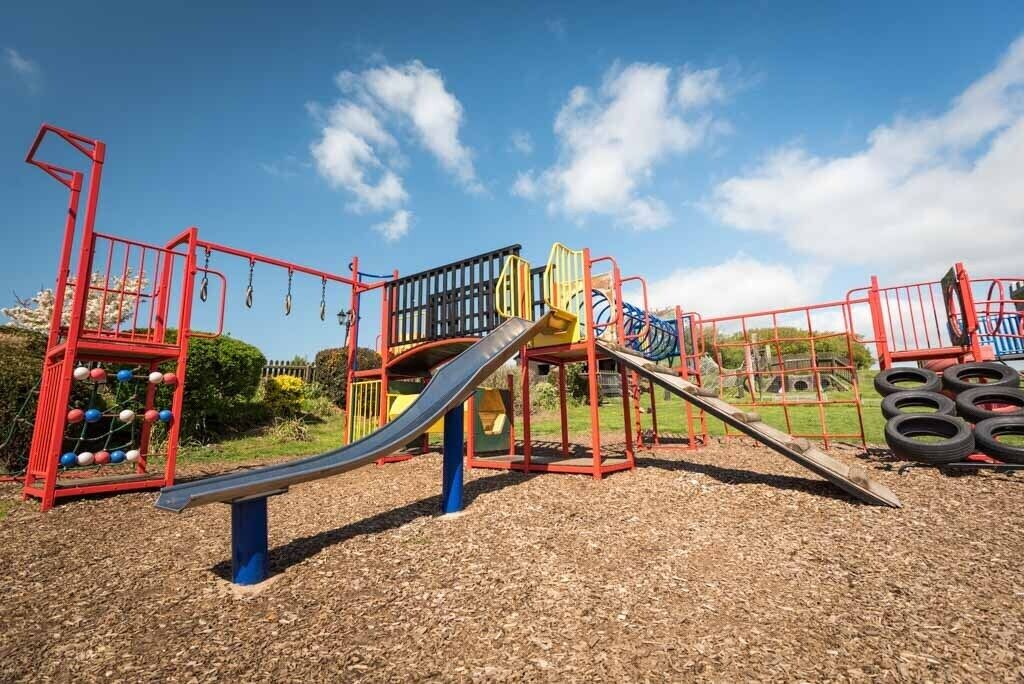 Un parque infantil con tobogán, estructuras para escalar y un balancín.
