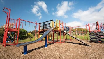 Un parque infantil con tobogán, estructuras para escalar y un balancín.