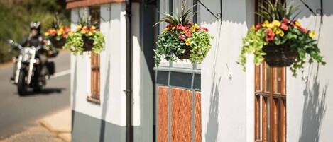 A row of white buildings with red-tiled roofs and hanging flower baskets.