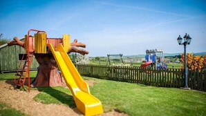 A playground with a slide, a swing set, and a fenced area. - The Chequers Inn (Ventnor)