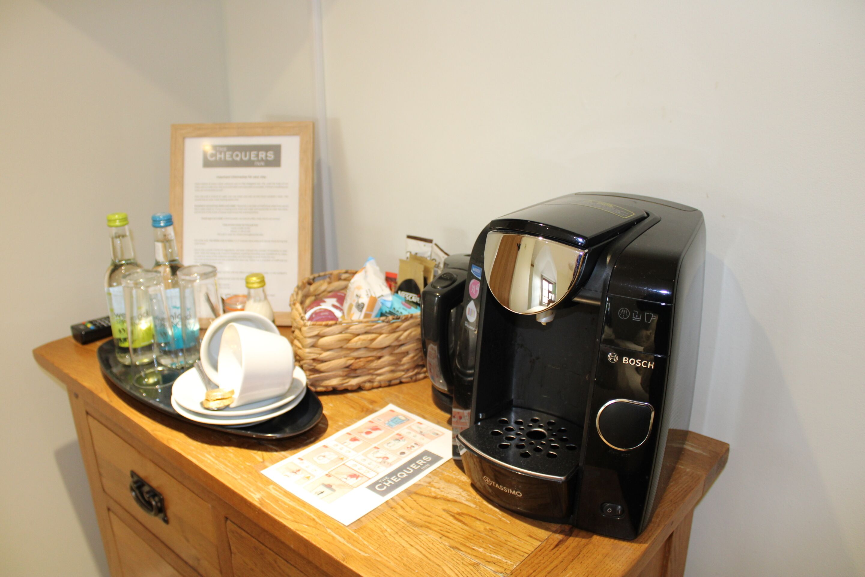 A coffee station with a coffee maker, cups, and condiments.