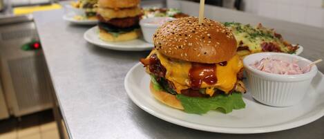 A restaurant setting with a counter displaying burgers and side dishes.