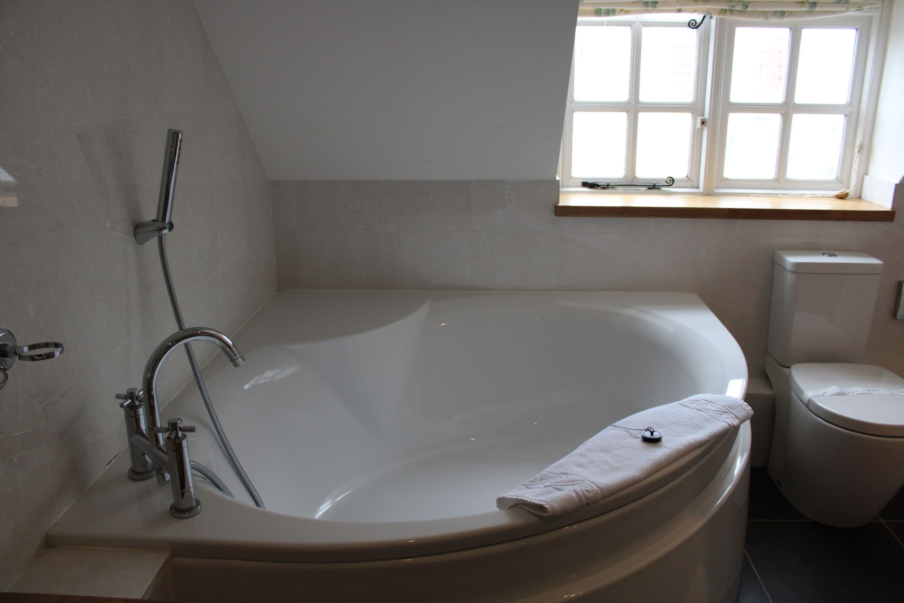 A bathroom with a freestanding bathtub, a toilet, and a window above the sink.