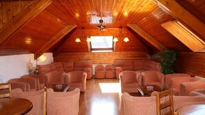 A cozy log cabin interior with a high ceiling, wooden walls, and a central seating area with sofas and chairs. - Hotel Escalar (Panticosa)