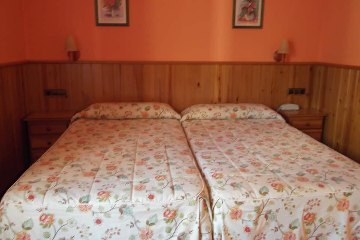 A double bed with floral bedding in a room with wooden paneling and two framed floral pictures on the wall.