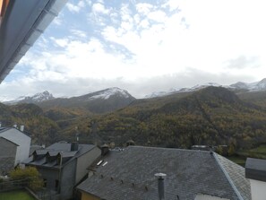 A mountain landscape with a view of a building with a sloped roof and chimneys. - Hotel Escalar (Panticosa)