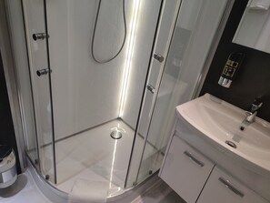 A modern bathroom with a glass shower enclosure, a white sink, and a mirror. - Hotel Corveyer Hof (Hoexter)