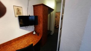 A room with a wooden desk, a flat-screen TV, and a framed picture on the wall. - Hotel Corveyer Hof (Hoexter)