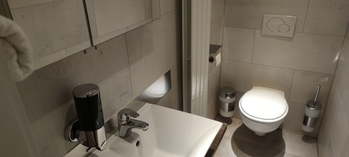 A bathroom with a white sink, a toilet, and a trash can.