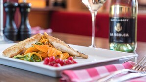A plate of food with a glass of wine and a bottle of wine on a table.