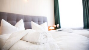 A hotel room with a large bed, a headboard, and a nightstand with a lamp.