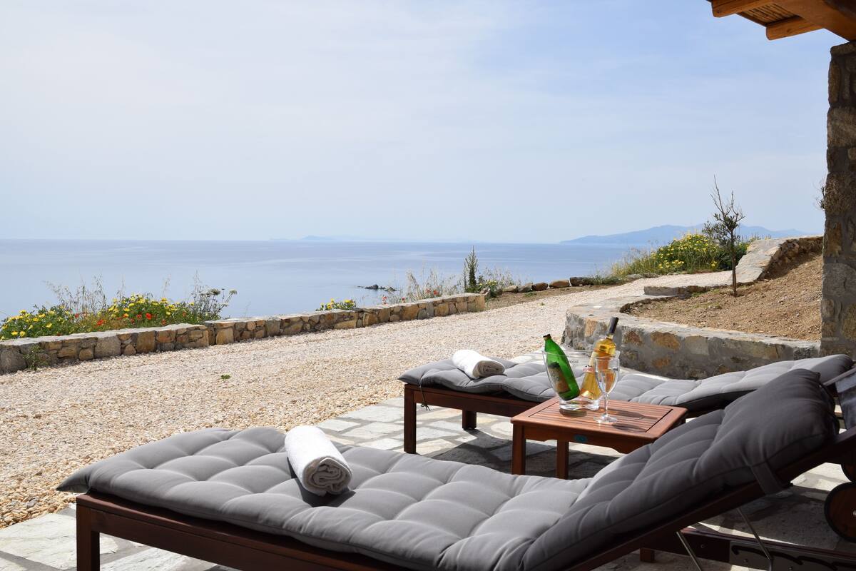 Eine Strandlounge mit gepolsterten Sitzgelegenheiten und einem Tisch, mit Blick auf das Meer.