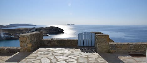 Um terraço de pedra com vista para o mar e um portão.