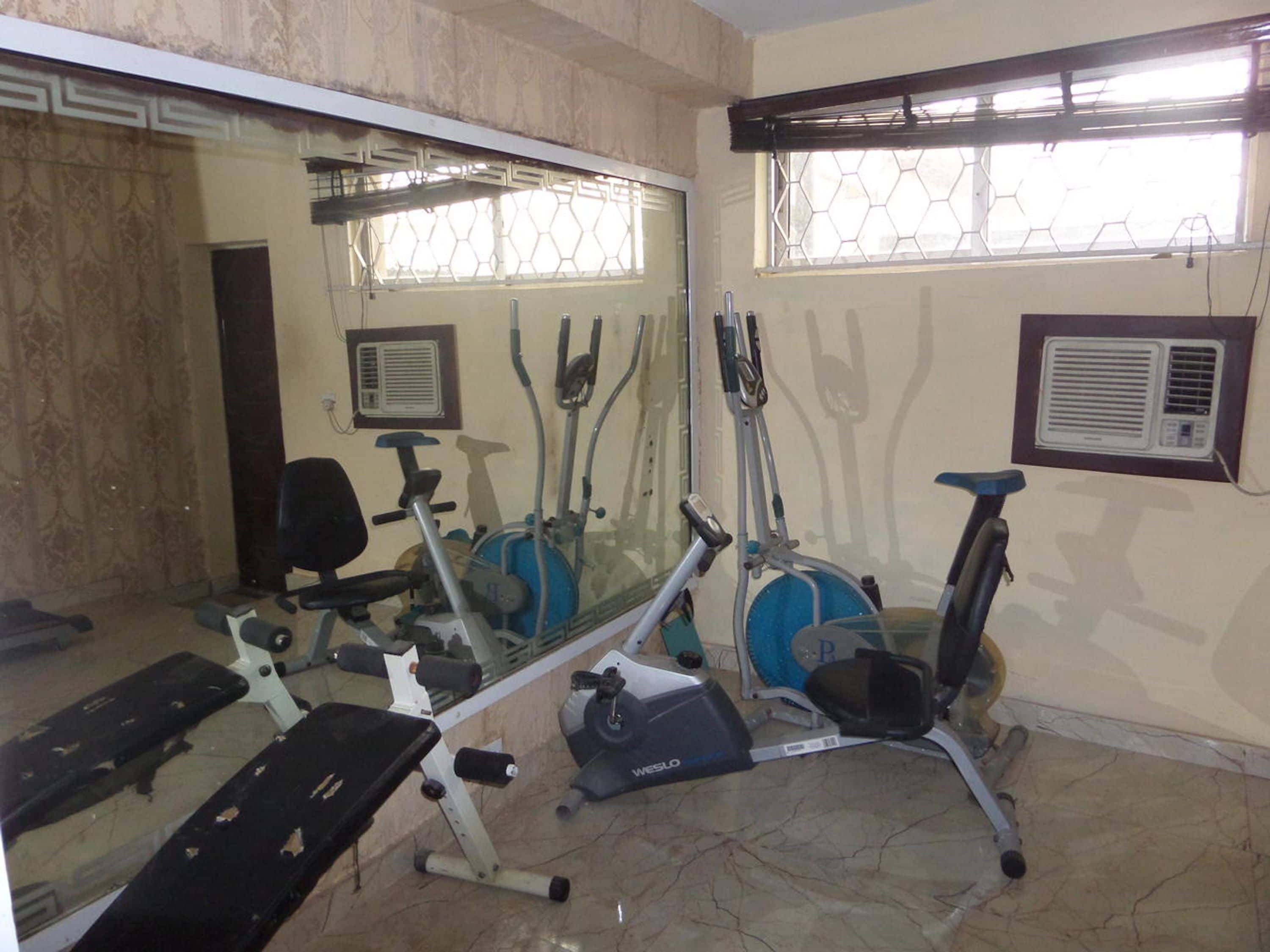 A gym with exercise equipment, a mirror, and a window with a hexagonal pattern.