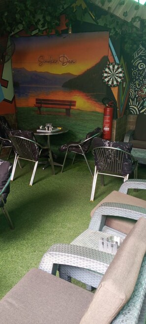 An outdoor seating area with a mural backdrop, a dartboard, and a fire extinguisher. - Belfem International Suites (Lagos)