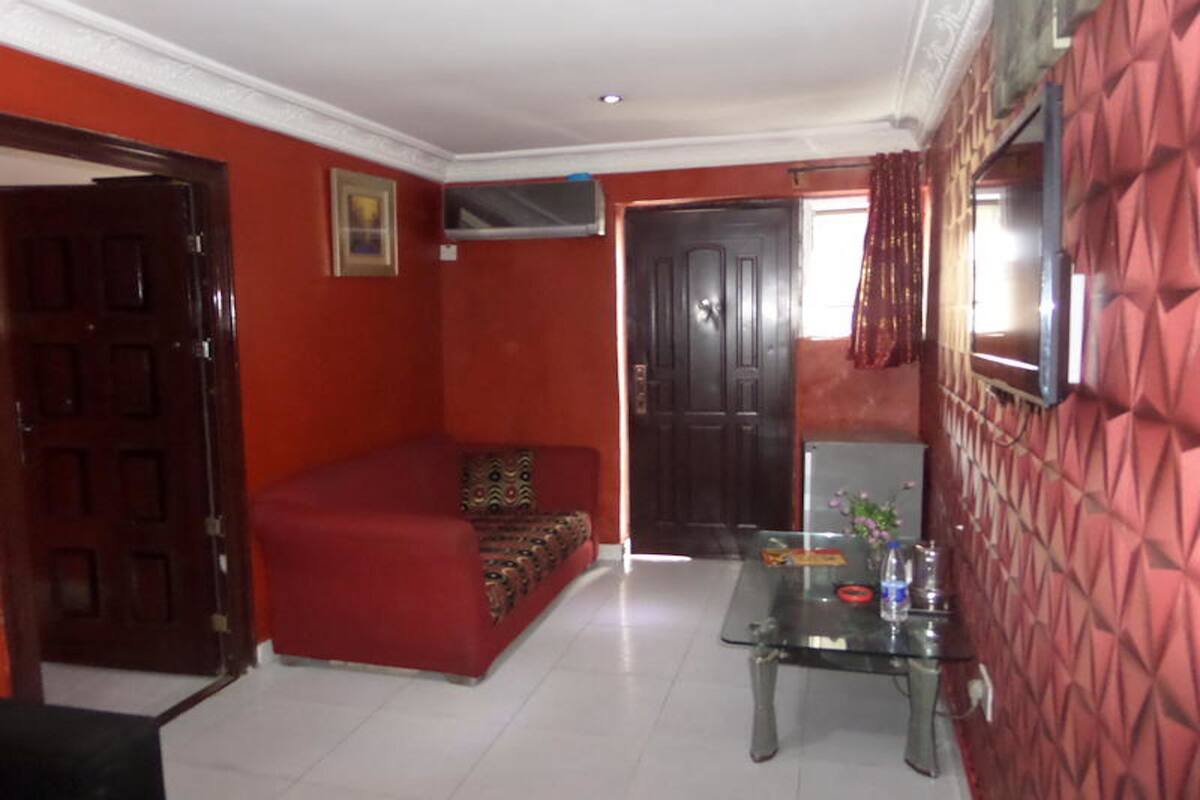 A room with a red sofa, a glass coffee table, and a door leading to another room.