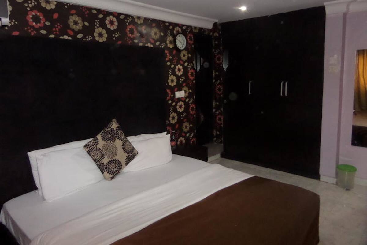 A bedroom with a bed, a clock, and a wardrobe.